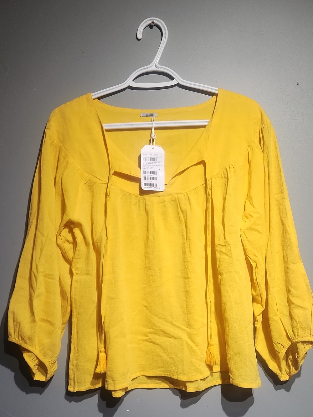 Yellow "Bata" (blouse) with a V-neckline and decorative tassels.